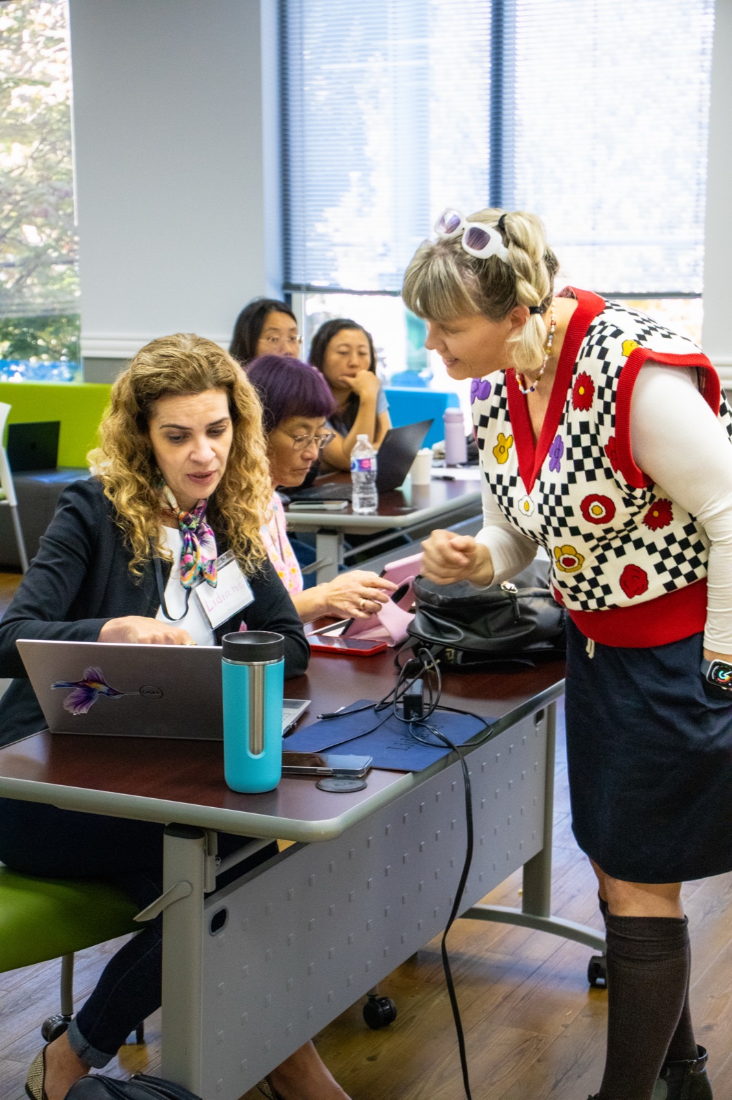 Lara leading a workshop, helping a participant at her laptop